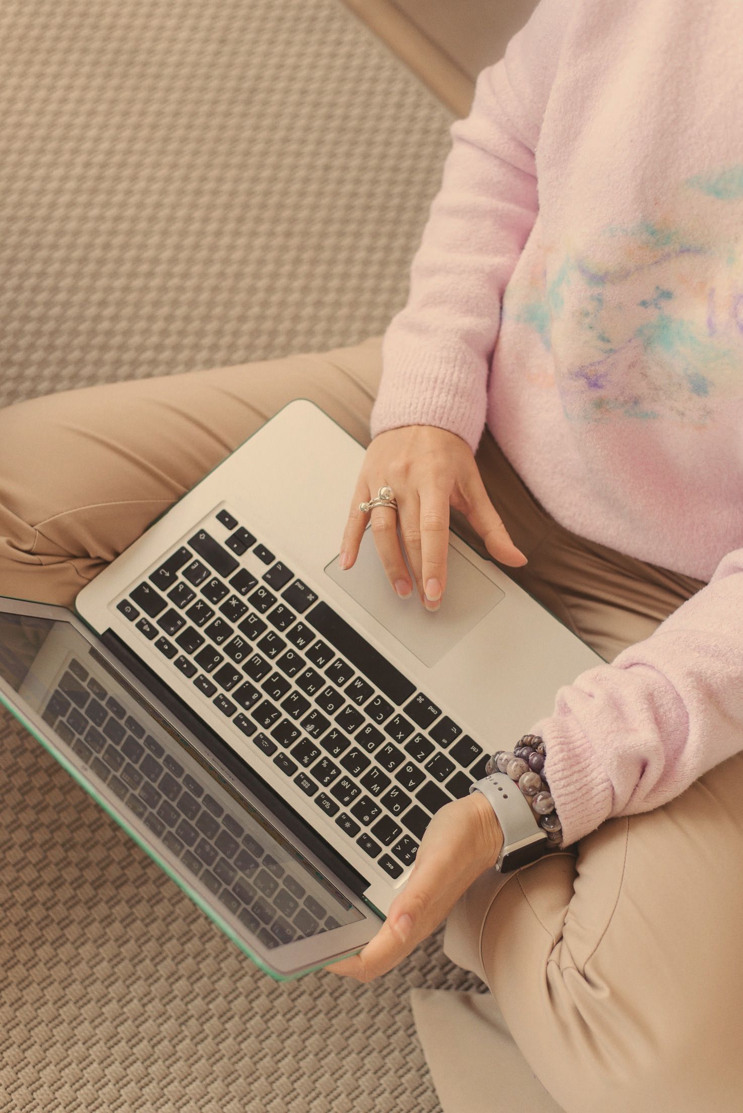 Overhead view of a woman working at a laptop on her lap in daylight.