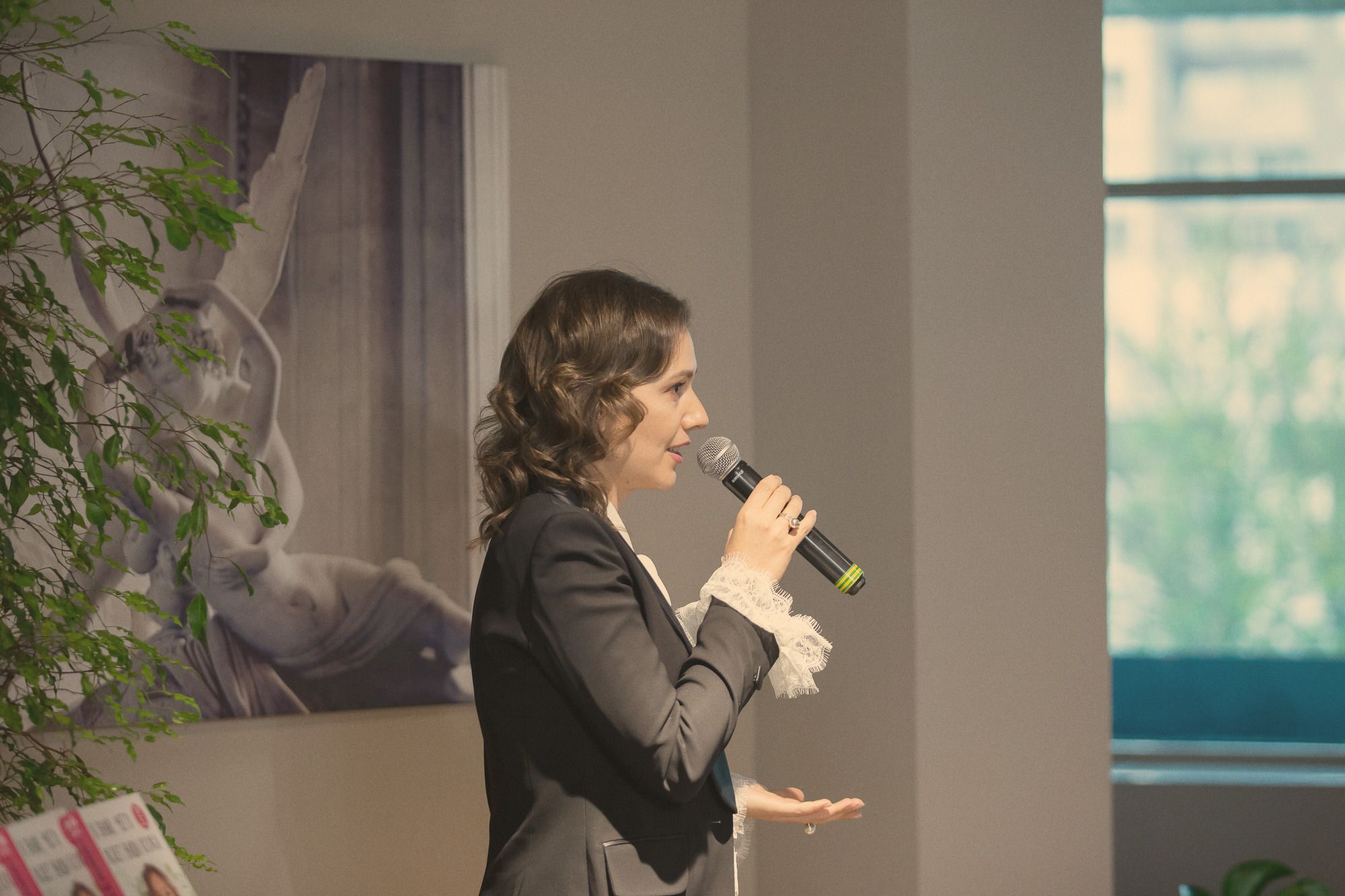 Natalia Dichkovska speaking into a microphone at a conference, profile view.